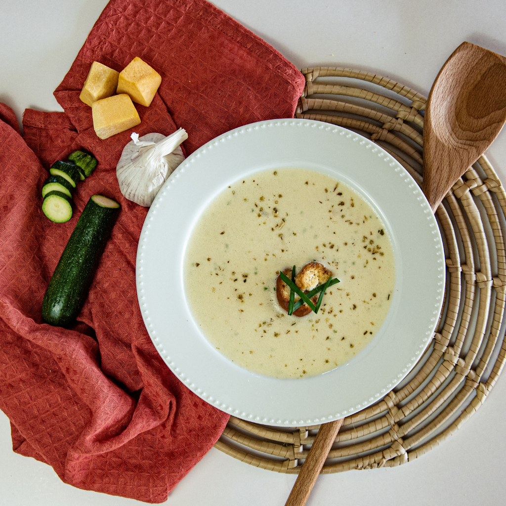 Prepared Vegetable Soup with vegetables and a cloth laid next to it on a place mat