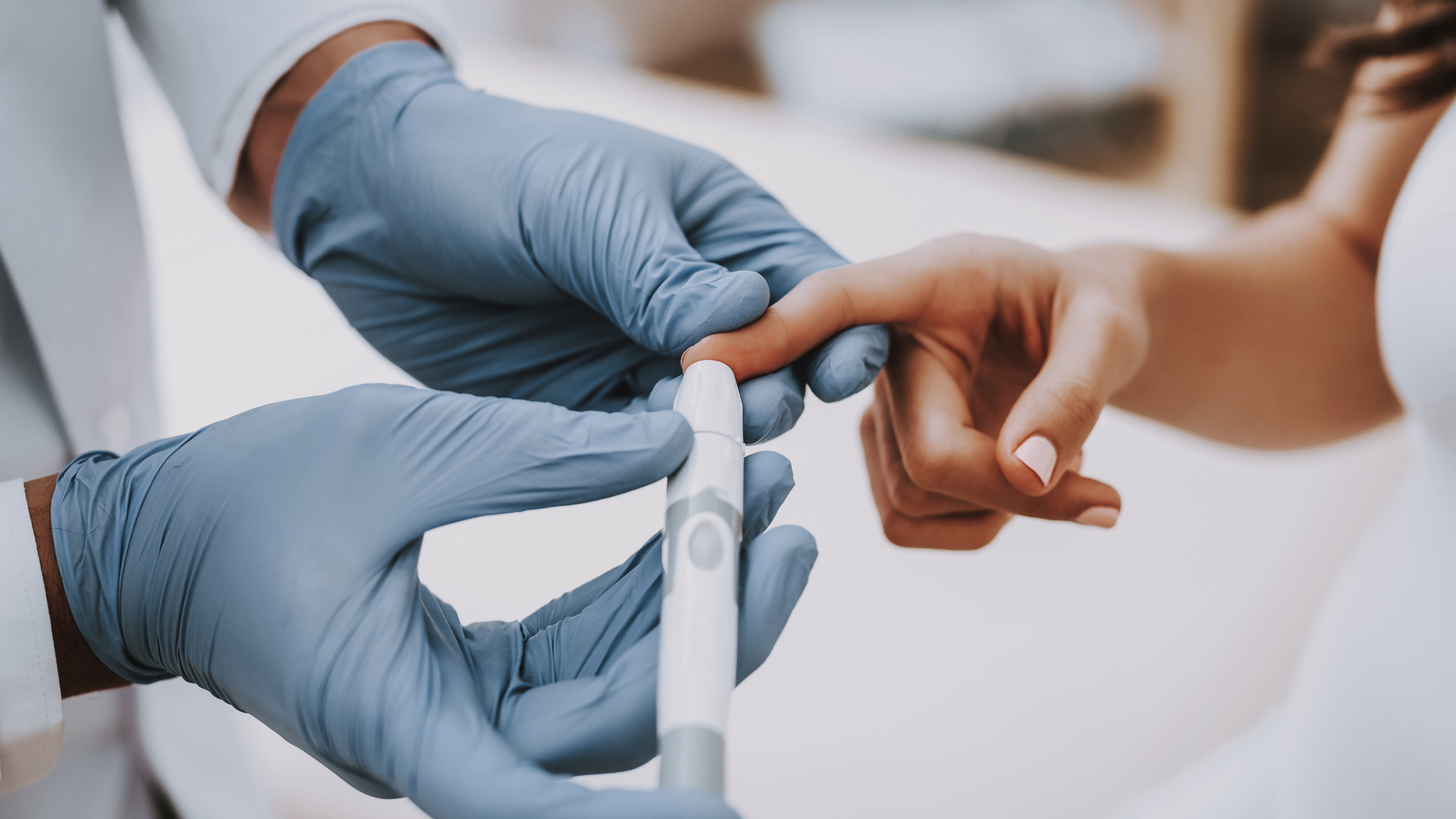 A person with gloves pricking someones finger with a lancing device 