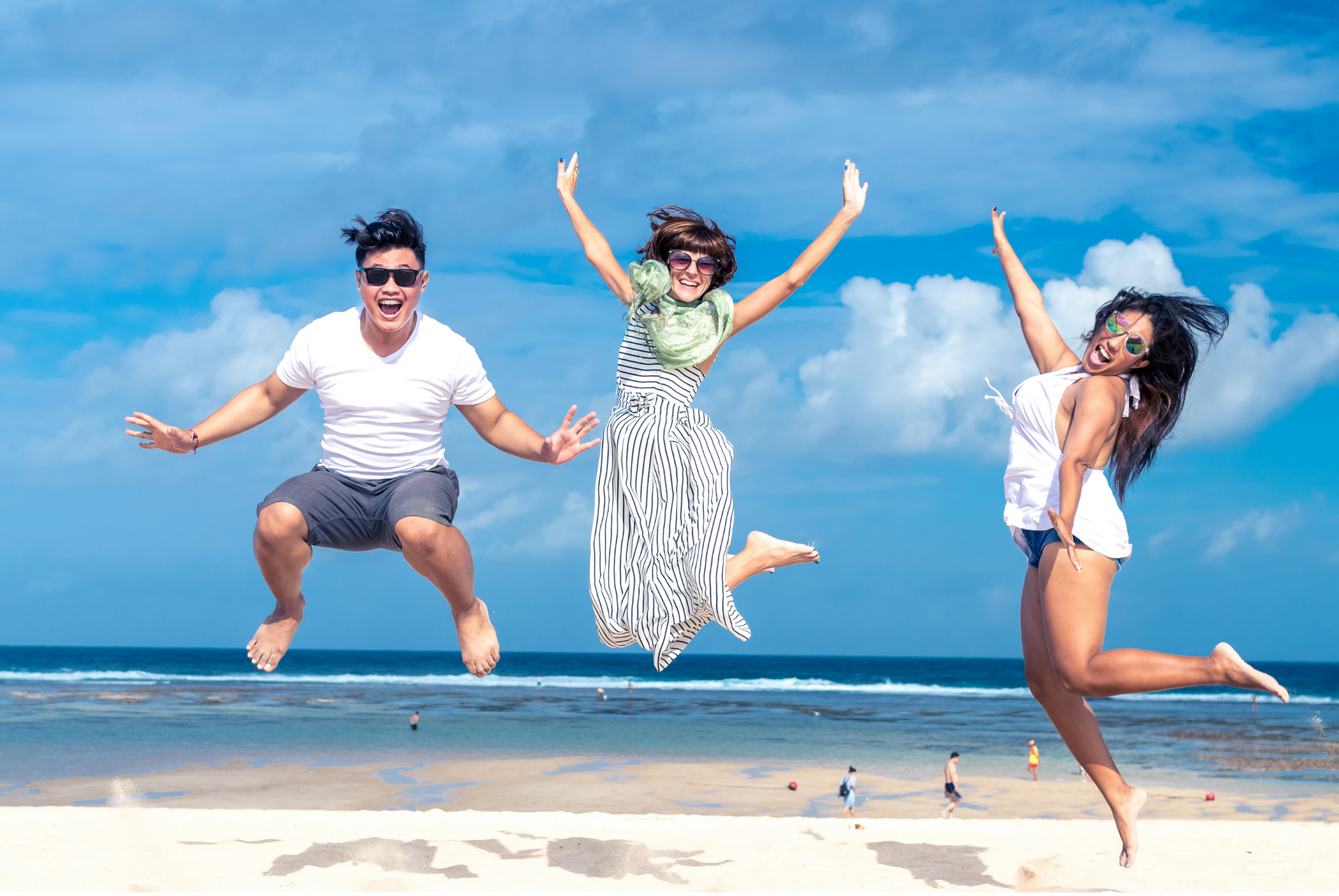 Three people at the beach jumping in the air