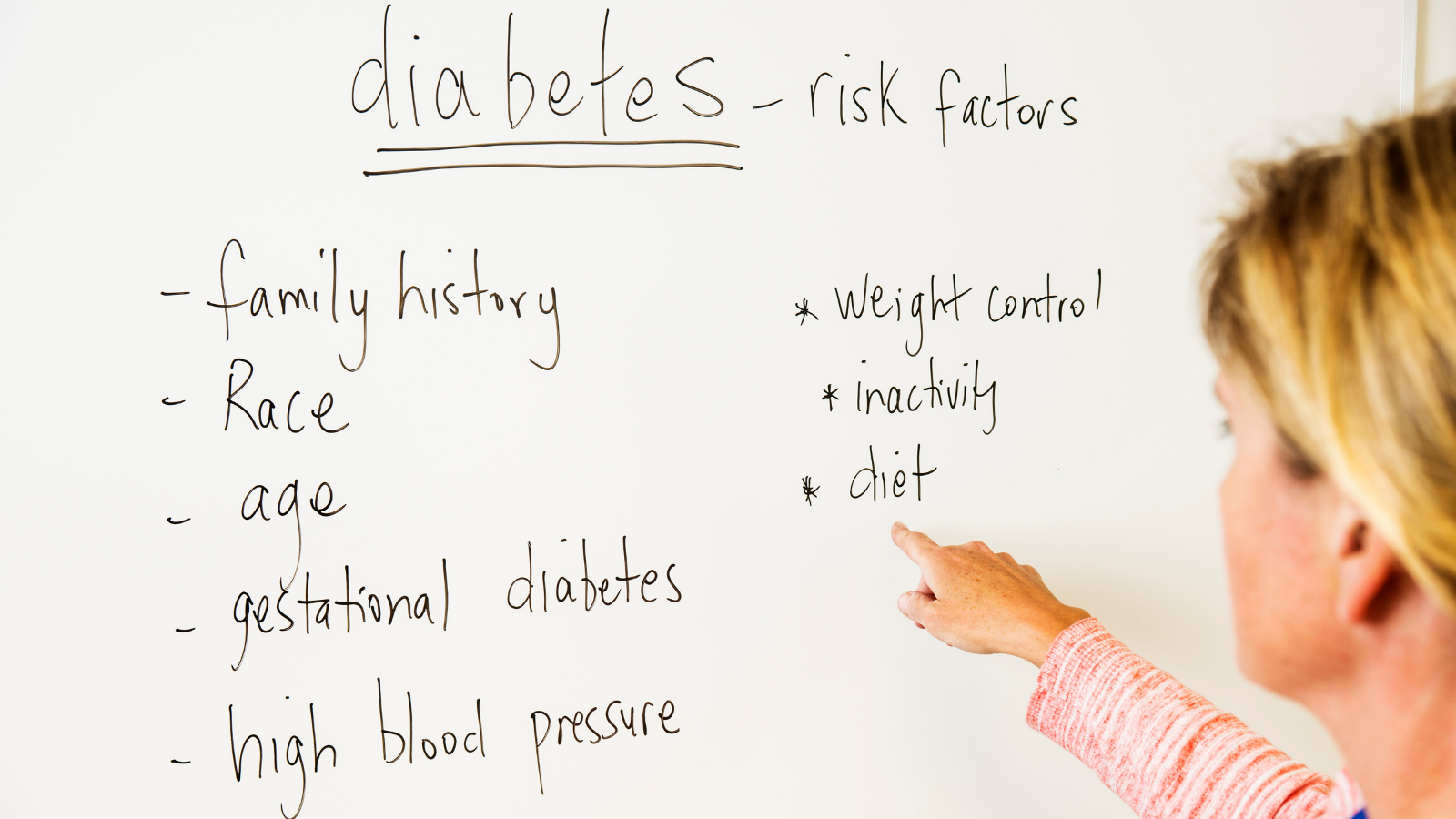 A person pointing at a white board about diabetes risk factors