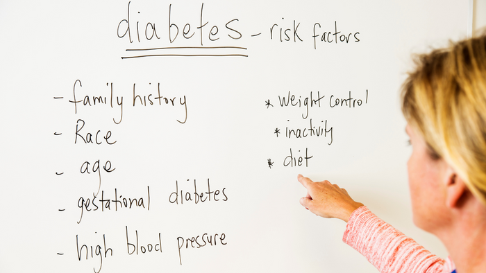 A person pointing at a white board about diabetes risk factors