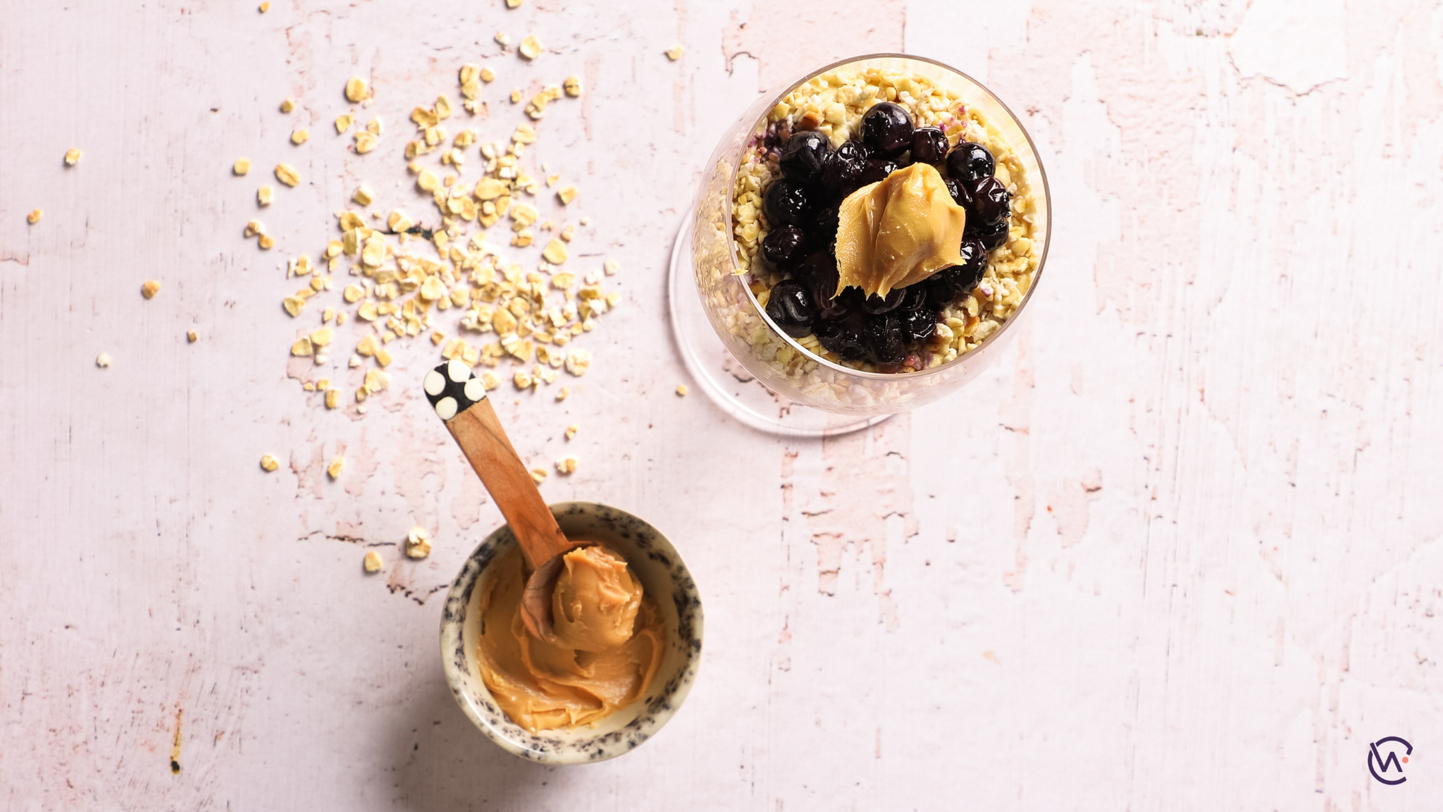 A glass of Peanut butter and blueberry porridge next to a jar of peanut butter