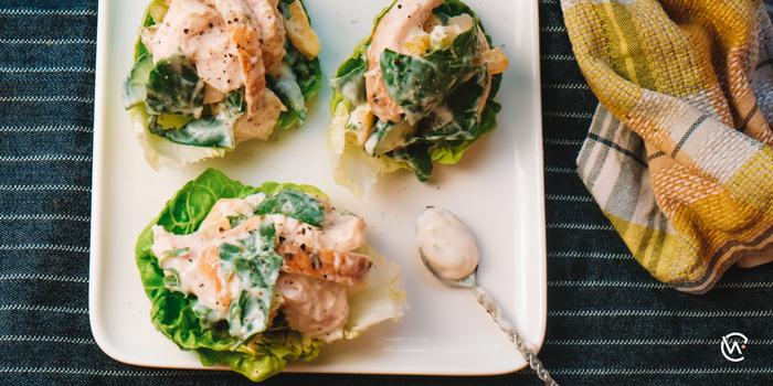A tray with three lettuce cups with chicken breast and yogurt inside