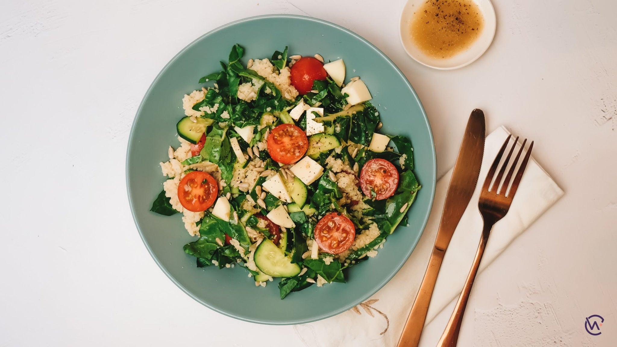 A colour salad on a plate with dressing on the side