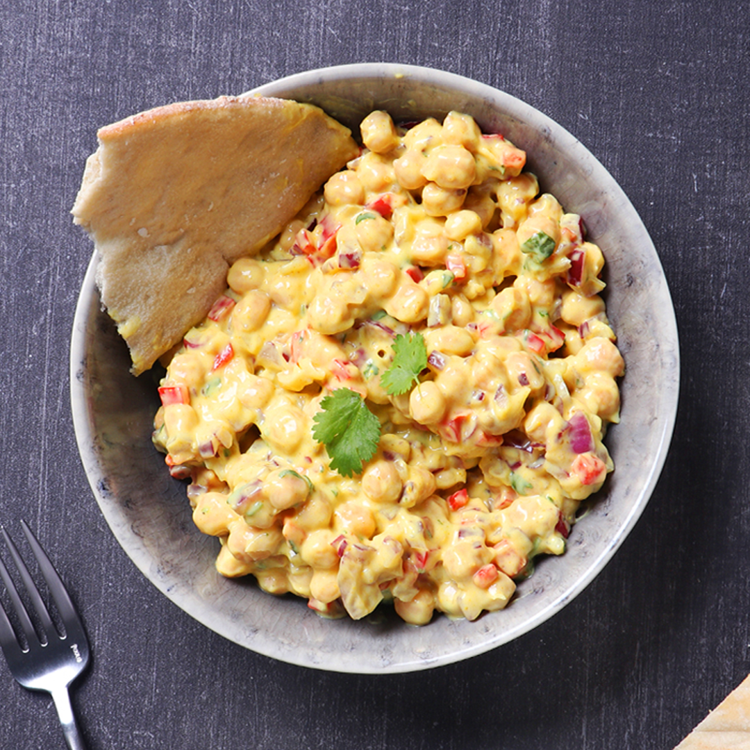 A bowl of chickpeas in a coronation sauce