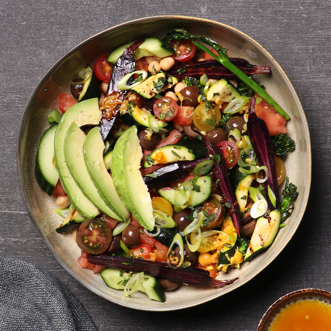 A large bowl of salad with avo on top