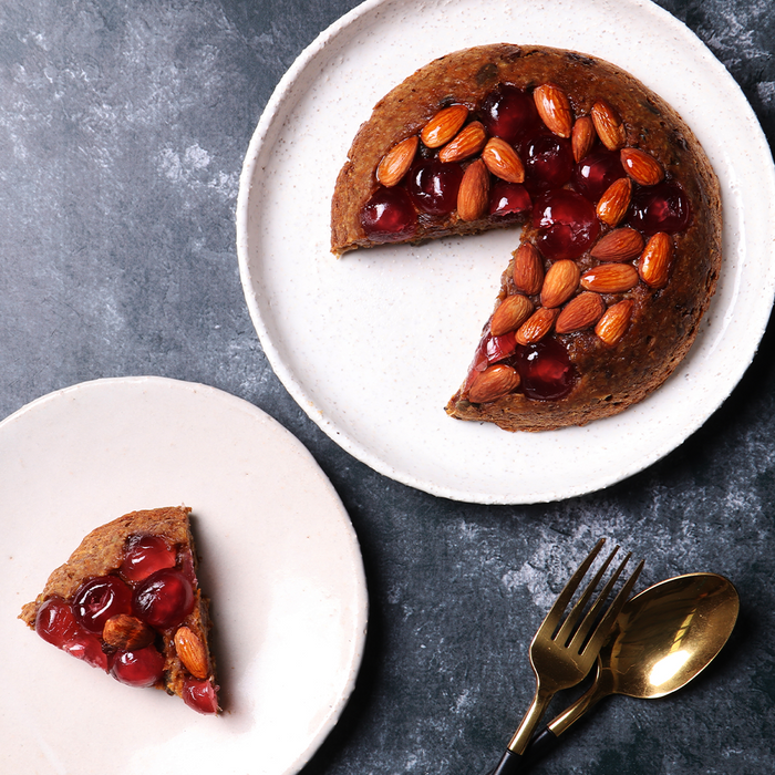 A christmas pudding with nuts and berries on top and a slice on a second plate