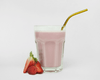 Prepared strawberry shake in a glass with a straw and berries next to it