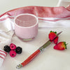 Prepared strawberry shake in a glass with berries, a knife and cloth next to it